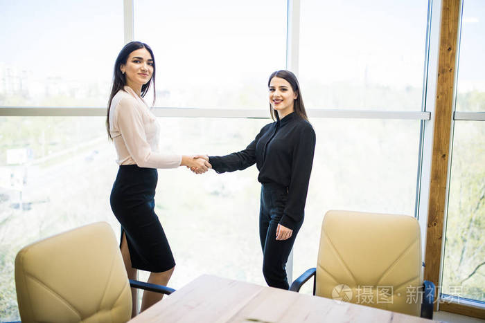 两个漂亮的女企业家在现代办公握手