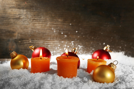 燃烧的蜡烛与圣诞玩具，木制背景上的雪