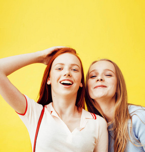 生活方式的人概念 两个漂亮的年轻学校少女开心快乐微笑在黄色背景上