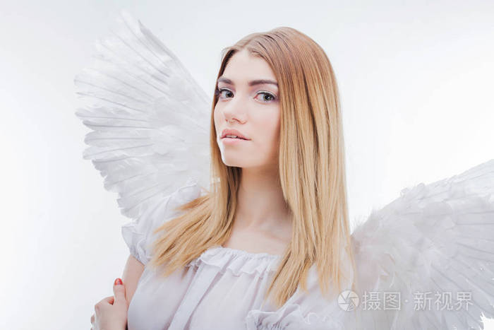 一位天使从天堂.在白色翅膀的天使形象年轻, 精彩的金发女郎