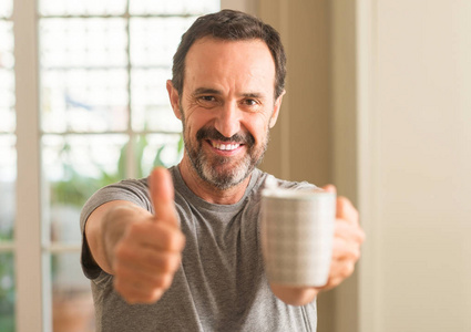 中年男子喝咖啡在一杯快乐的大微笑做 ok 标志, 拇指与手指, 优秀的标志