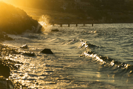 石海滩与波浪和以金黄彩色太阳灯在晚上