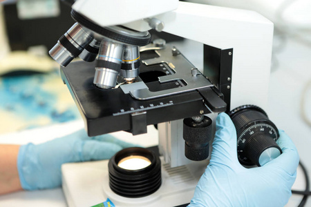 一个女人和一个男人研究药物颗粒在显微镜下的结构。悬浮在显微镜下放大后的粉末颗粒的质量。实验室的质量制药厂