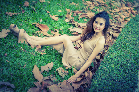 亚洲漂亮的女孩坐在公园的绿色的草地上的肖像
