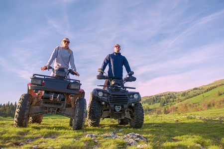 美丽的情侣看着夕阳从山上坐在亚视 quadbike