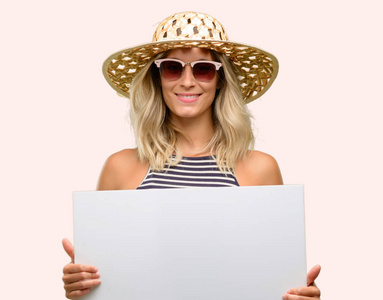 戴着夏季帽子的年轻女子手持空白广告横幅, 广告的好海报, 要约或公告, 大纸广告牌