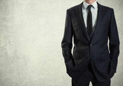 在水泥墙背景下穿西装的男人照片