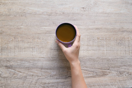 一杯咖啡在女性手上的木材纹理背景