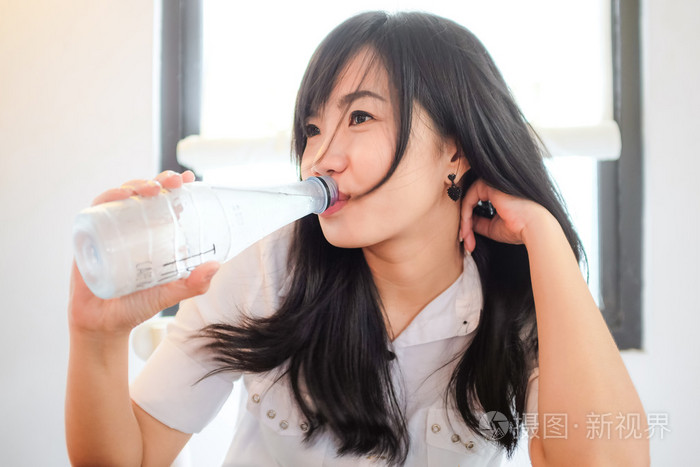 年轻漂亮的亚洲女人喝水的肖像