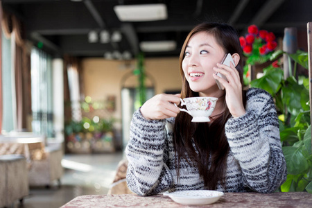 移动电话在咖啡馆里的中国女人