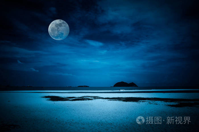 美丽的热带海滩的海景在夜间.迷人明亮的满月在黑暗的天空与多云.宁静