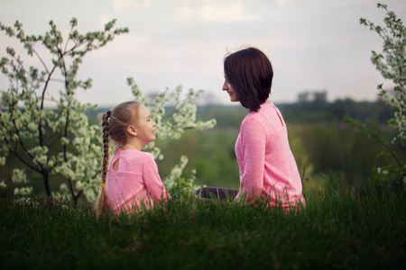 夏天的时候, 小女孩和她妈妈坐在草地上。从后面查看