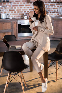 女人喝咖啡和使用的便携式计算机