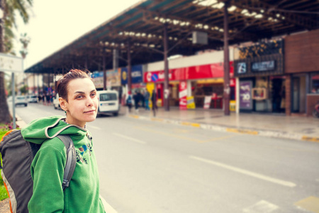 一个背着背包的女孩在城里四处走动。游客检查景点。那个女人在旅行。微笑的黑发人像