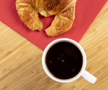 红餐巾上有羊角面包的咖啡杯