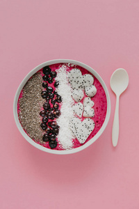 美味的冰鲜碗与浆果, 椰子片, 嘉籽和 dragonfruit 件在粉红色的背景