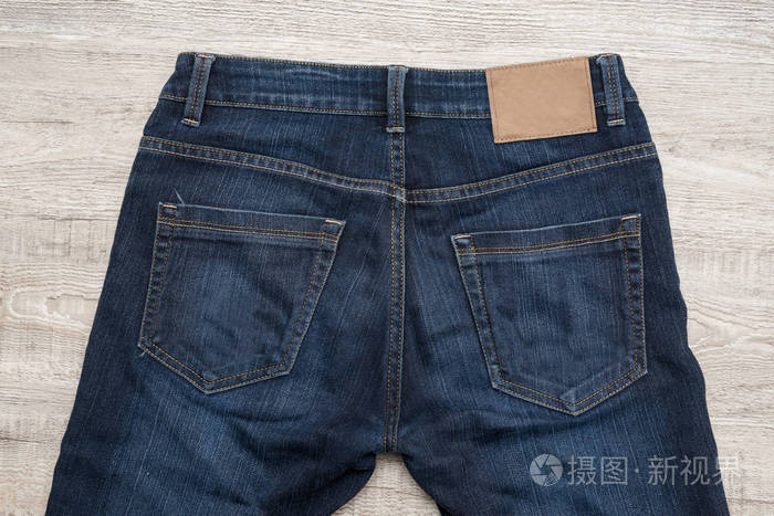 背面蓝色牛仔裤的木材背景与棕色皮革标签横幅