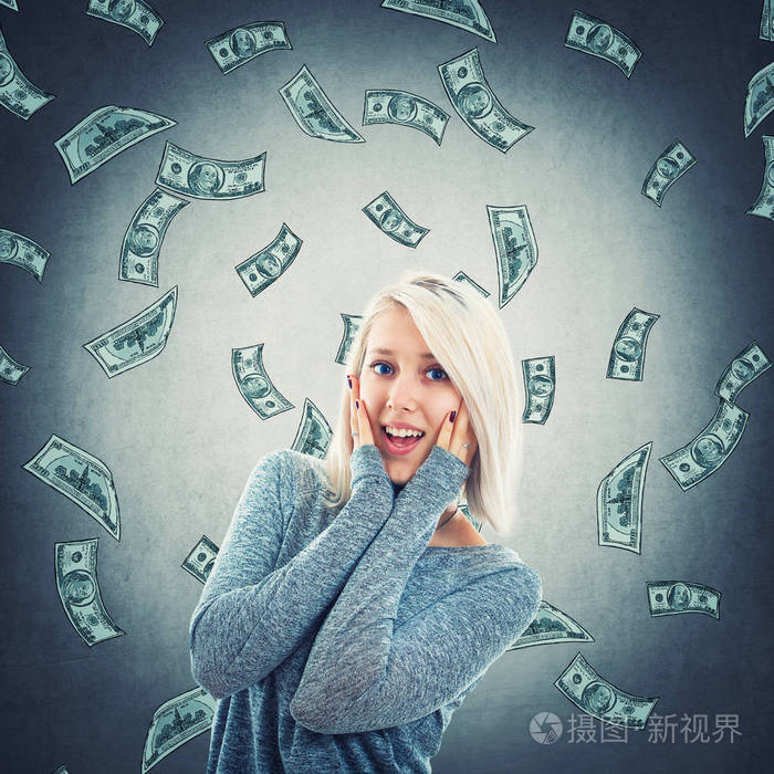一个惊讶的女人, 手放在脸颊上, 张开嘴巴, 因为钱正从天上掉下来.
