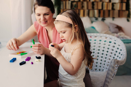 母亲和蹒跚学步的女儿玩橡皮泥或玩橡皮泥在家。幸福的家庭舒适周末早上学习