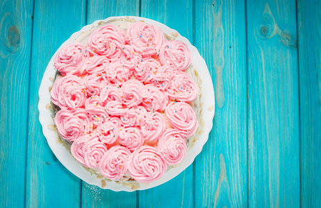 在蓝色木背景粉色奶油蛋糕。粉色蛋糕