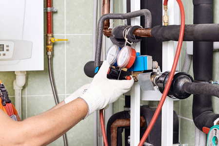 维修工程师检查锅炉房供暖系统设备的技术数据。住宅供暖系统的水管工安装压力表
