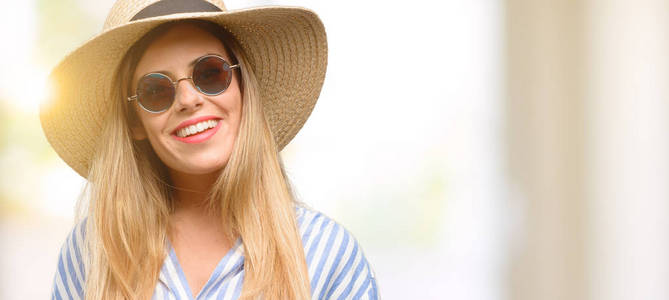 戴着太阳镜和夏日帽子的年轻女子自信而快乐地笑着大笑