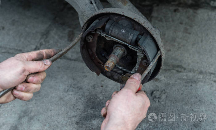 修理汽车刹车鼓的人用两个螺丝刀检查刹车垫