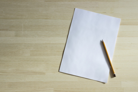 弄皱的纸和一支铅笔白色空白张纸和一支铅笔,躺在一张小木桌上照片