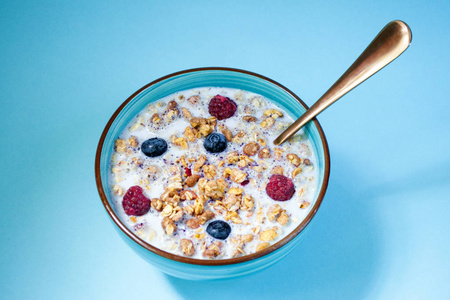 碗健康麦片早餐与浆果和牛奶, 麦片, 玉米。在蓝色背景上