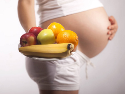 怀孕妇女拿着一个盘子与果子, 演播室隔绝了