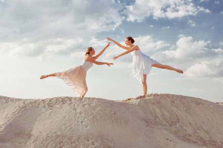 两个年轻的舞者在沙漠中跳舞在沙子上