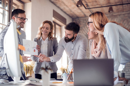 一群年轻的商界人士在办公室里一起工作, 在餐桌上看书, 用电脑照片