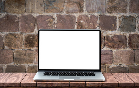 现代笔记本电脑空白色屏幕上的木桌上对模糊旧砖墙