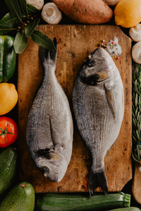 带香料和不同蔬菜的木木板上的金鱼鱼