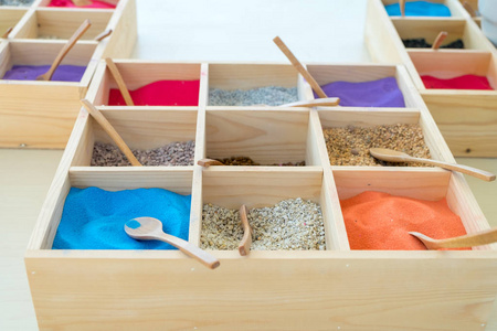 各种颜色的沙子放在一个小托盘制成的木材用来教艺术