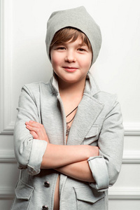 在灰色的帽子和外套在浅色背景上的酷年轻时尚男孩的肖像
