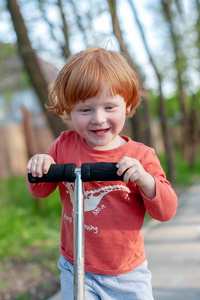 一个微笑的男孩骑着滑板车