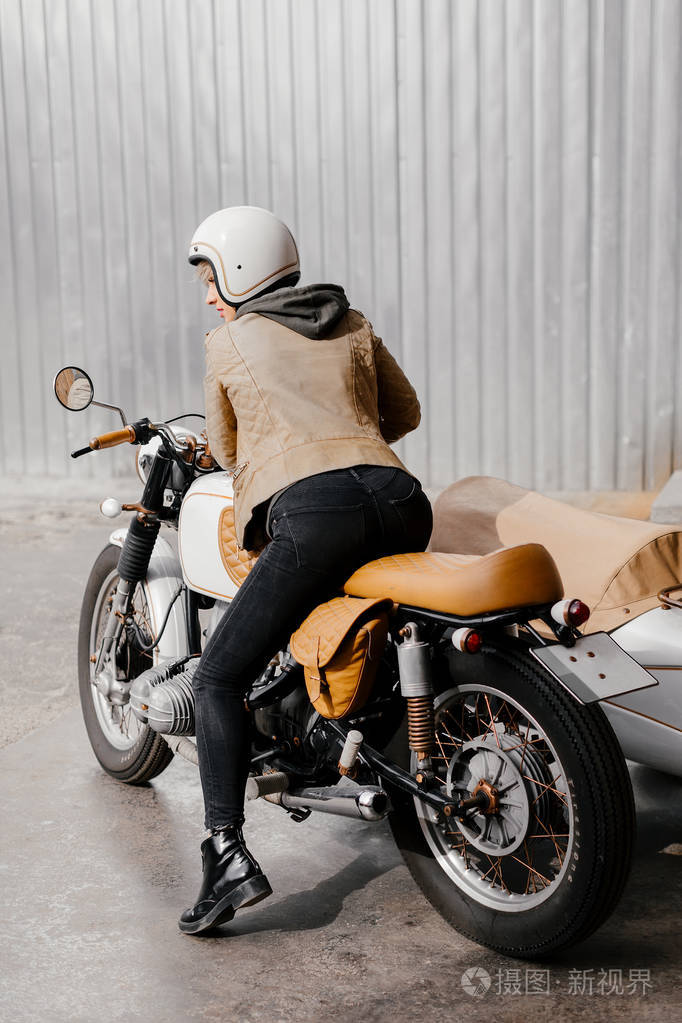 小女孩微笑着一辆摩托车从后面的女孩的照片年轻的女子在一辆摩托车