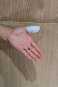 用白色纱布和包扎胶带在拳头受伤拇指木墙纸墙
