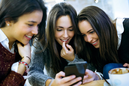 三个年轻漂亮的女性在咖啡店使用手机