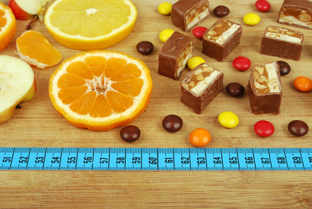 糖果 水果和一把尺子在木板上