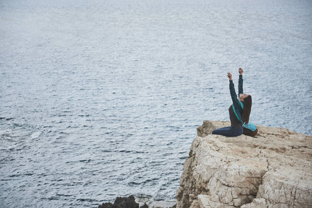 轻松的年轻女子正在岩石山上享受海风