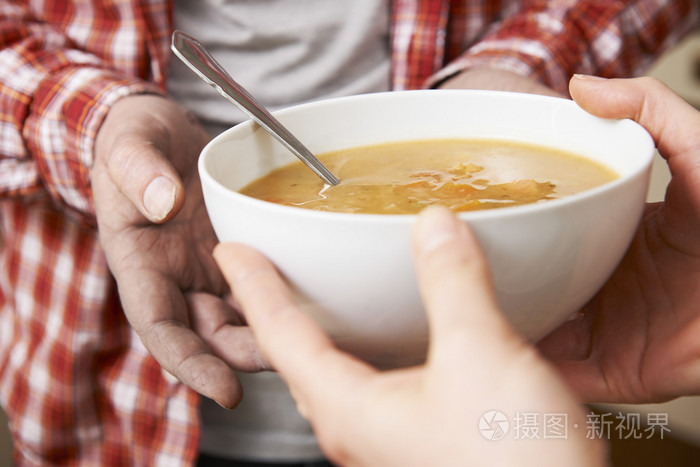 无家可归的人正在通过志愿者递碗汤