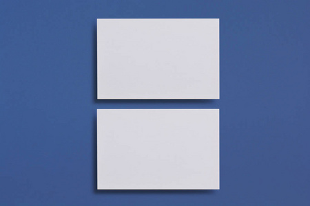 在蓝色纹理的纸张背景下, 模拟两张水平白色名片。用于品牌标识的模型模板。为平面设计师介绍和组合