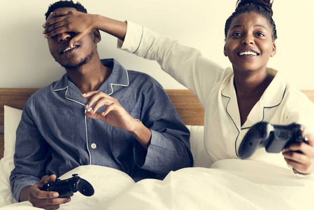 一对快乐的情侣在床上玩电子游戏