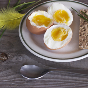 新鲜的煮的鸡蛋和绿色葱在木制的桌子上的盘子。健康的早餐