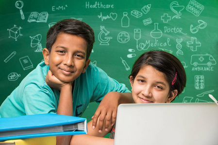 印度学校的孩子们在教室里使用笔记本电脑，在绿色黑板背景用乱