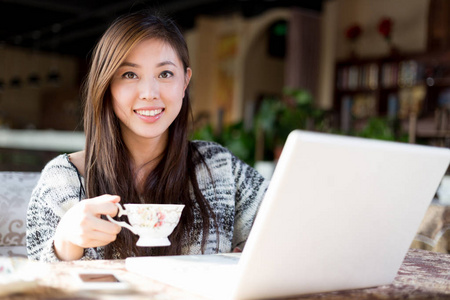 笔记本电脑在咖啡馆的年轻中国女子
