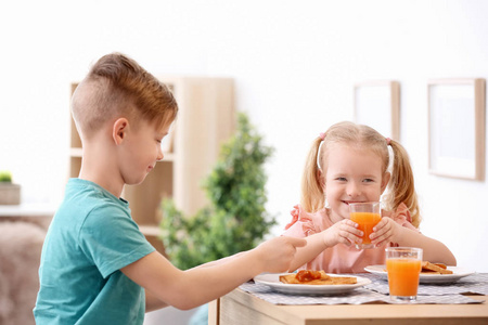 可爱的小孩子吃可口的烤面包与果酱在桌上