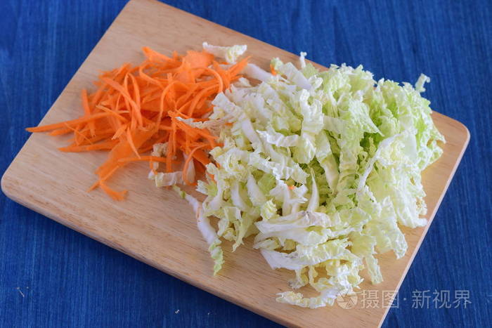 切碎的白菜和胡萝卜放在一个木制砧板.一步一步走烹饪